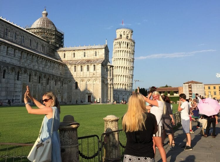 Laikydami pasvirusį Pizos bokštą Italijoje