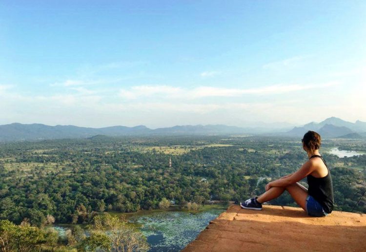 Woman sitting on Sigiriya Rock with mountains in the background