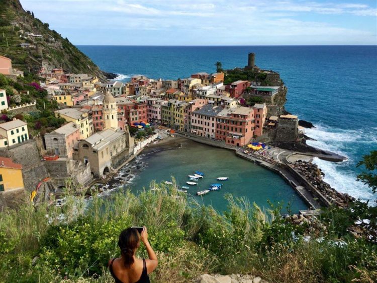 Woman taking a photo at Vernazza in Cinque Terre in Italy
