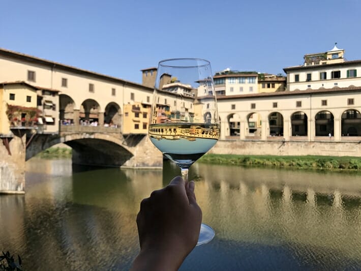 Glass of white wine in front of Ponte Vecchio in Florence