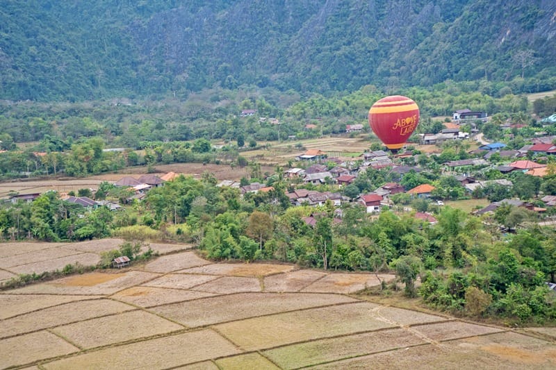 Hot air balloon flying over villages in Vang Vieng Laos