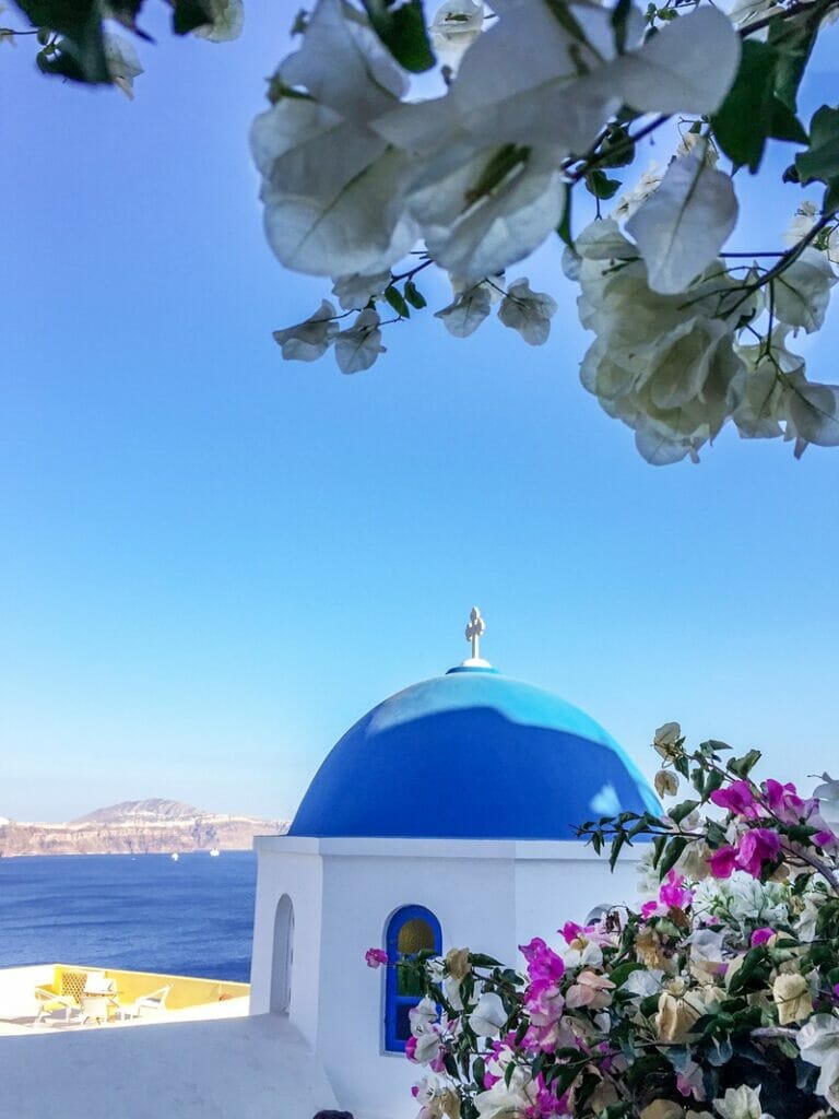 Bougainvillea and blue church dome in Santorini Greece