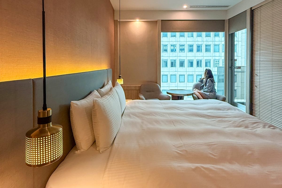 Woman starting out of bedroom window in a boutique hotel in Taipei Taiwan